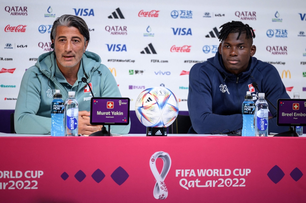 Switzerland's coach Murat Yakin (L) and Switzerland's forward #07 Breel Embolo (R) attend a press conference in Doha on December 5, 2022, on the eve of the Qatar 2022 World Cup Round of 16 football match between Portugal and Switzerland. (Photo by Fabrice COFFRINI / AFP)