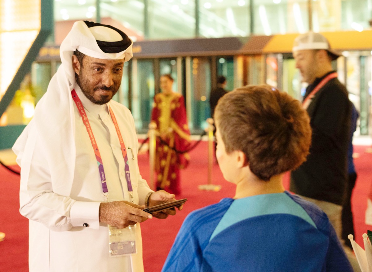 Abdulla Al Qahtani at a World Cup stadium interacting with a child.