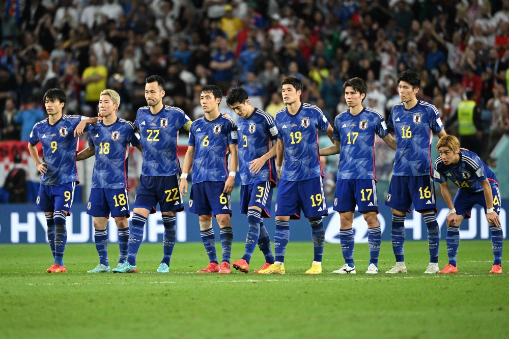 Japan's players stand together at the start of the penalty shootout during the Qatar 2022 World Cup round of 16 football match between Japan and Croatia at the Al-Janoub Stadium in Al-Wakrah, south of Doha on December 5, 2022. (Photo by Ina Fassbender / AFP)