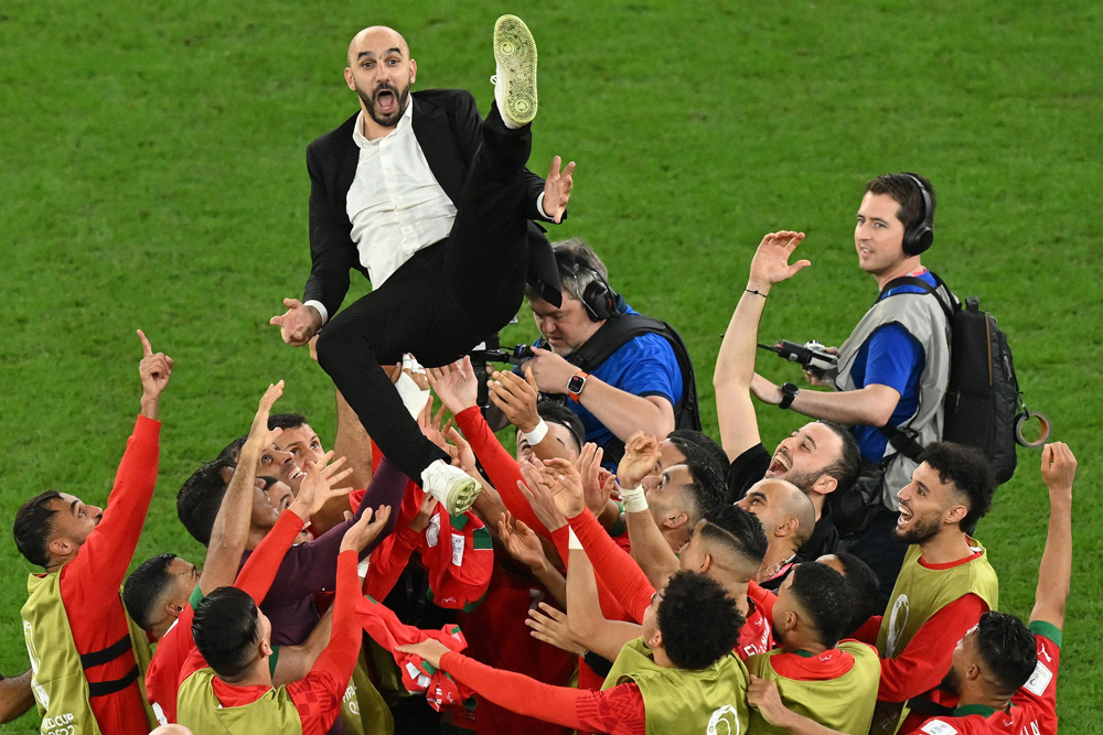 Morocco’s players throw coach Walid Regragui in the air as they celebrate after defeating Spain on Tuesday. AFP