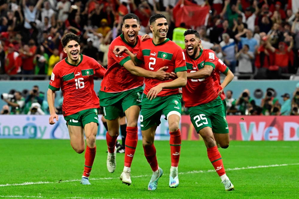 Morocco's defender Achraf Hakimi (centre) celebrates with teammates after converting the last penalty during the penalty shoot-out to win the Qatar 2022 World Cup round of 16 match between against Spain at the Education City Stadium in Al-Rayyan, west of Doha, on December 6, 2022. (Photo by JAVIER SORIANO / AFP)