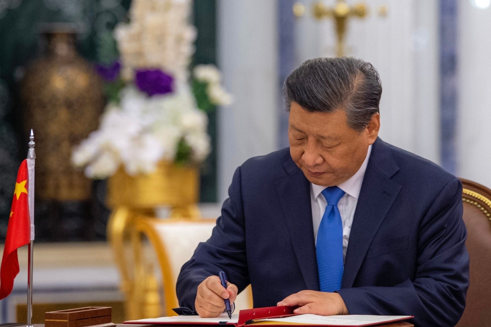 This handout picture provided by the Saudi Royal Palace shows Chinese President Xi Jinping signing an agreement with the Custodian of the Two Holy Mosques, King Salman bin Abdulaziz Al-Saud of the Kingdom of Saudi Arabia (not pictured), in the capital Riyadh, on December 8, 2022. (Photo by BANDAR AL-JALOUD / AFP) 