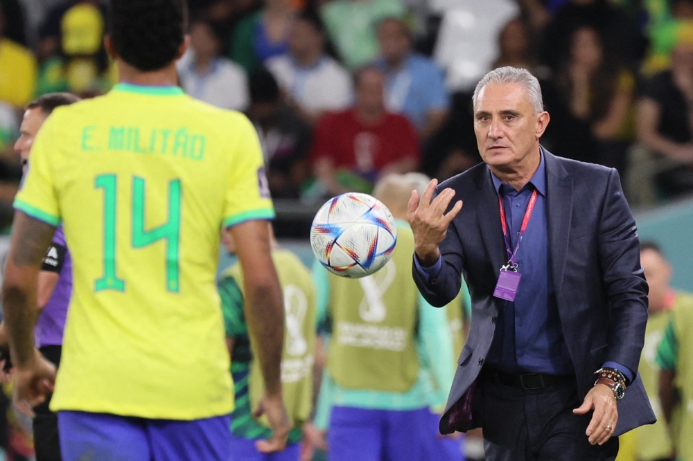 Brazil's coach Tite throws the ball to Brazil's Eder Militao during the Qatar 2022 World Cup quarter-final football match between Croatia and Brazil at Education City Stadium on December 9, 2022. (Photo by JACK GUEZ / AFP)