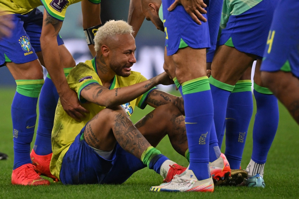 Brazil's Neymar is consoled by teammates after they lost the Qatar 2022 World Cup quarter-final match against Croatia at Education City Stadium on December 9, 2022. (Photo by NELSON ALMEIDA / AFP)