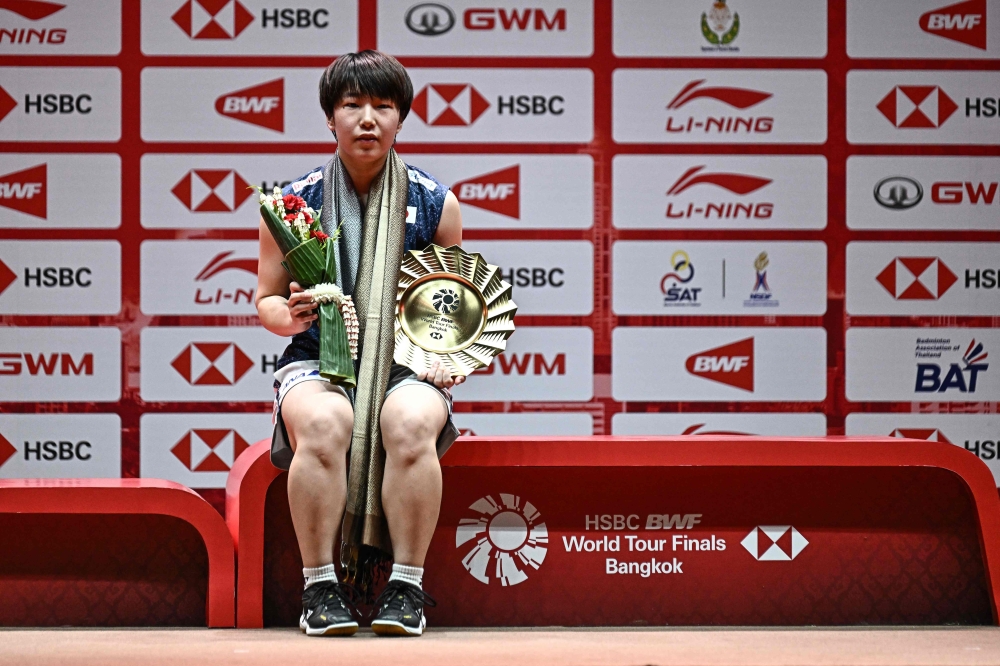 Japan's Akane Yamaguchi holds the winner's trophy after her victory against Taiwan's Tai Tzu-ying in Bangkok on December 11, 2022. (Photo by Lillian Suwanrumpha / AFP)