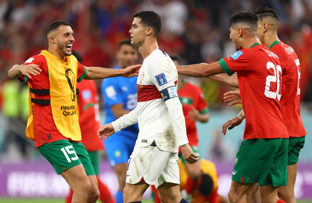 Portugal's Cristiano Ronaldo looks dejected after being eliminated from the World Cup as Morocco players celebrate after progressing  into the semi finals at the Al Thumama Stadium, Doha, Qatar, on December 10, 2022.  REUTERS/Carl Recine 