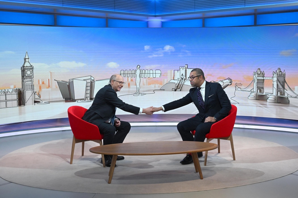 A handout picture released by the BBC, taken and received on December 11, 2022, shows Britain's Foreign Secretary James Cleverly (right) shaking hands with Medical Director of NHS England, Stephen Powis during an appearance on the BBC's 'Sunday Morning' political television show with journalist Laura Kuenssberg at the BBC headquarters in London. (Photo by Jeff OVERS / BBC / AFP)