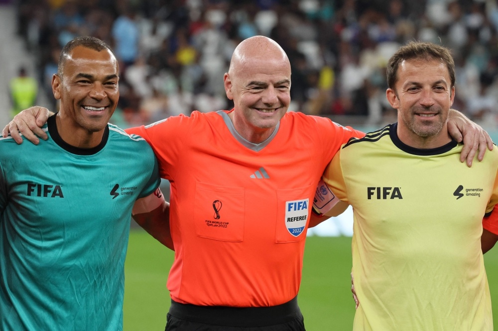 FIFA President Gianni Infantino (centre) wearing a referee uniform poses with former Brazilian footballer Cafu (left) and former Italian footballer Alessandro Del Piero as he officiates the friendly match of FIFA Legends and Qatar-based workers at Al Thumama Stadium in Doha on December 12, 2022. (Photo by KARIM JAAFAR / AFP)
 