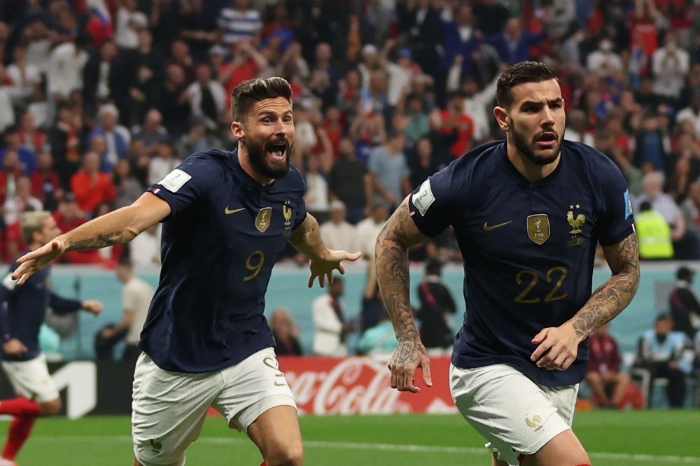 France's defender Theo Hernandez celebrates, with France's forward Olivier Giroud running behind, after scoring his team's first goal during the semi-final match on December 14, 2022. (Photo by Adrian Dennis / AFP)