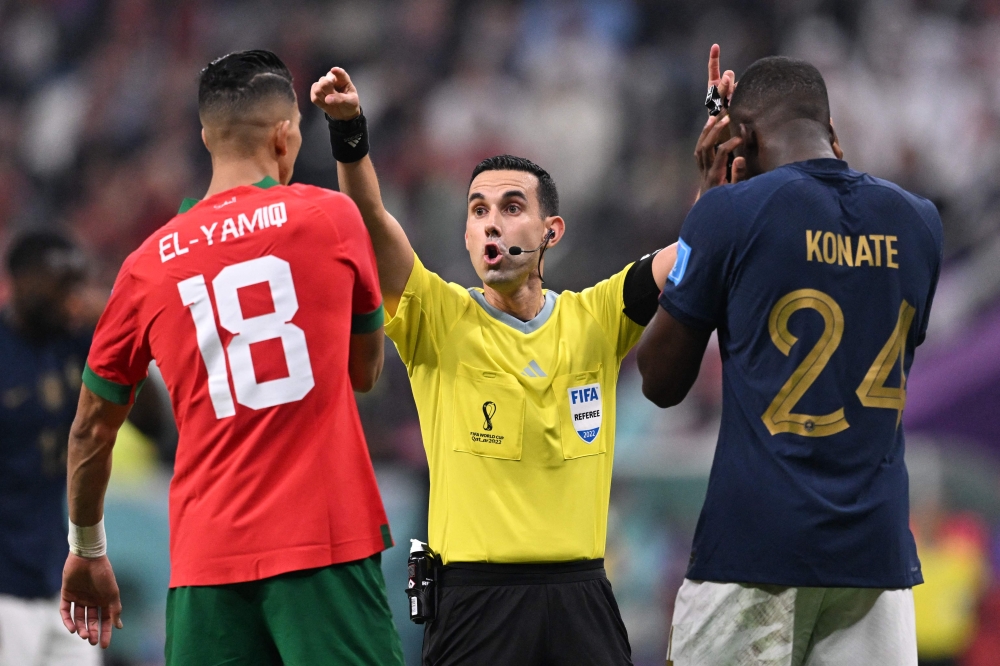 Mexican referee Cesar Ramos waves away Morocco's defender Jawad El Yamiq and France's defender Ibrahima Konate during the Qatar 2022 World Cup semi-final match between France and Morocco at the Al-Bayt Stadium on December 14, 2022. (Photo by Kirill Kudryavtsev / AFP)