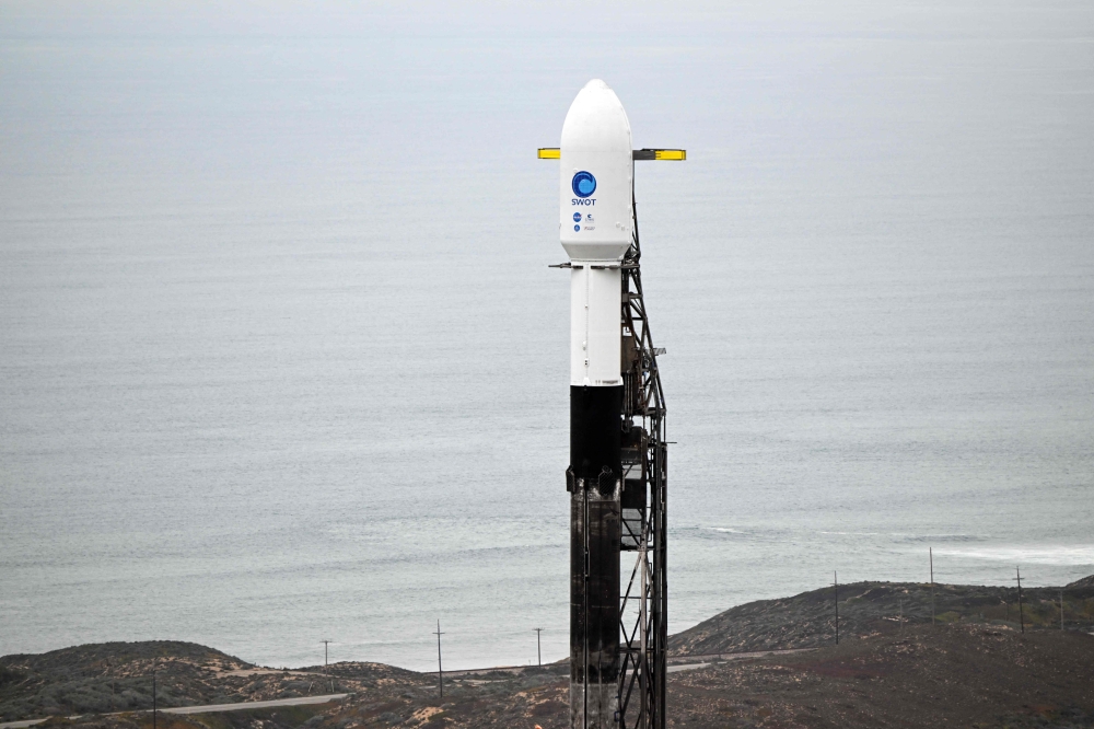 A SpaceX Falcon 9 rocket stands on a launch pad with the Surface Water and Ocean Topography (SWOT) satellite from NASA and France's space agency CNES at the Vandenberg Space Force Base in Lompoc, California on December 15, 2022. Photo by Patrick T. Fallon / AFP