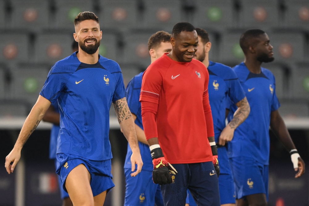 France's forward Olivier Giroud (left) and France's goalkeeper Steve Mandanda take part in a training session at the Al Sadd SC training centre in Doha on December 17, 2022, on the eve of the Qatar 2022 World Cup football final match between Argentina and France. (Photo by FRANCK FIFE / AFP)