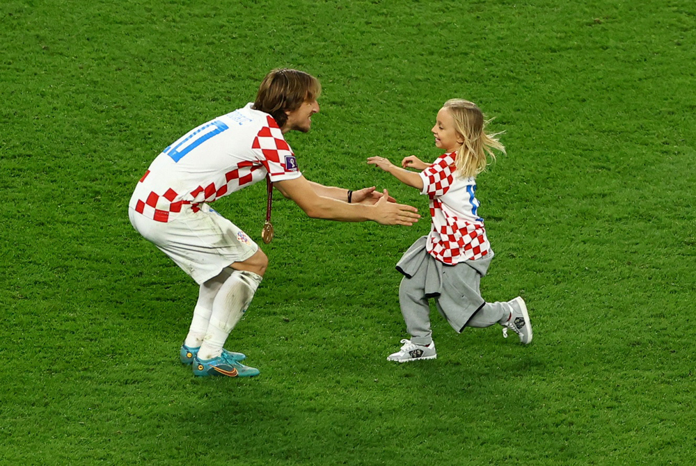 Luka Modric wears his medal as he celebrates with his daughter on the pitch after Croatia finished in third place.