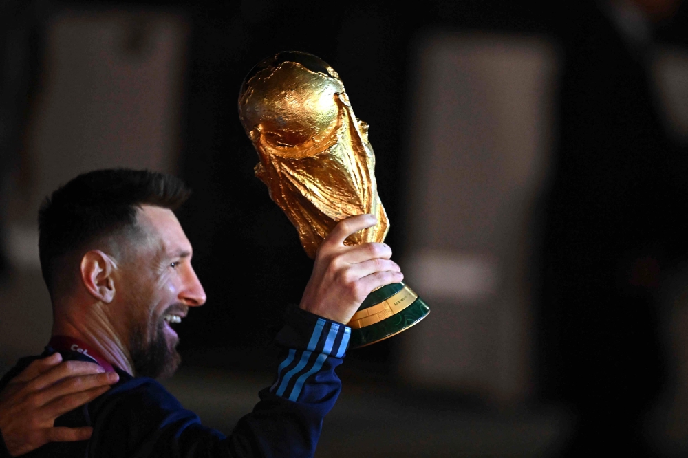 Argentina's captain and forward Lionel Messi holds the FIFA World Cup Trophy upon arrival at Ezeiza International Airport after winning the Qatar 2022 World Cup tournament in Ezeiza, Buenos Aires province, Argentina on December 20, 2022. (Photo by Luis ROBAYO / AFP)