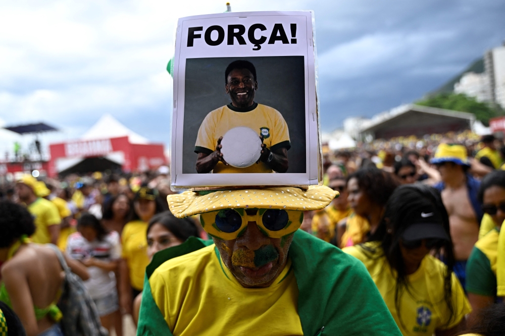 In this file photo taken on December 05, 2022 a fan of Brazil wears a hat with an image of Brazilian football legend Pele ahead of the start of the Qatar 2022 World Cup round of 16 football match between Brazil and South Korea at the FIFA Fan Festival in Copacabana beach, Rio de Janeiro, Brazil. (Photo by MAURO PIMENTEL / AFP)
 