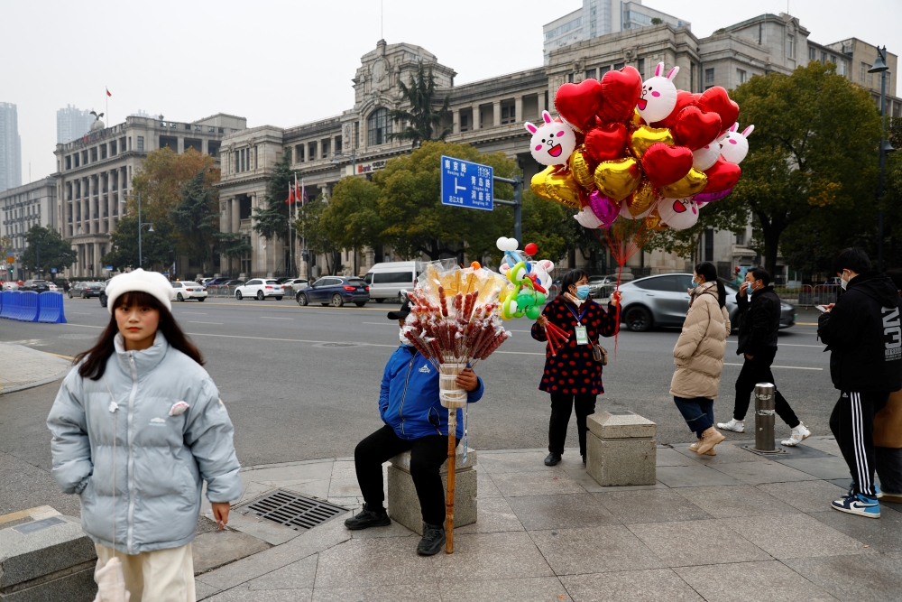 People walk past a ballon vendor, amid the coronavirus disease (Covid-19) outbreak, in Wuhan, Hubei province, China, on December 31, 2022. REUTERS/Tingshu Wang