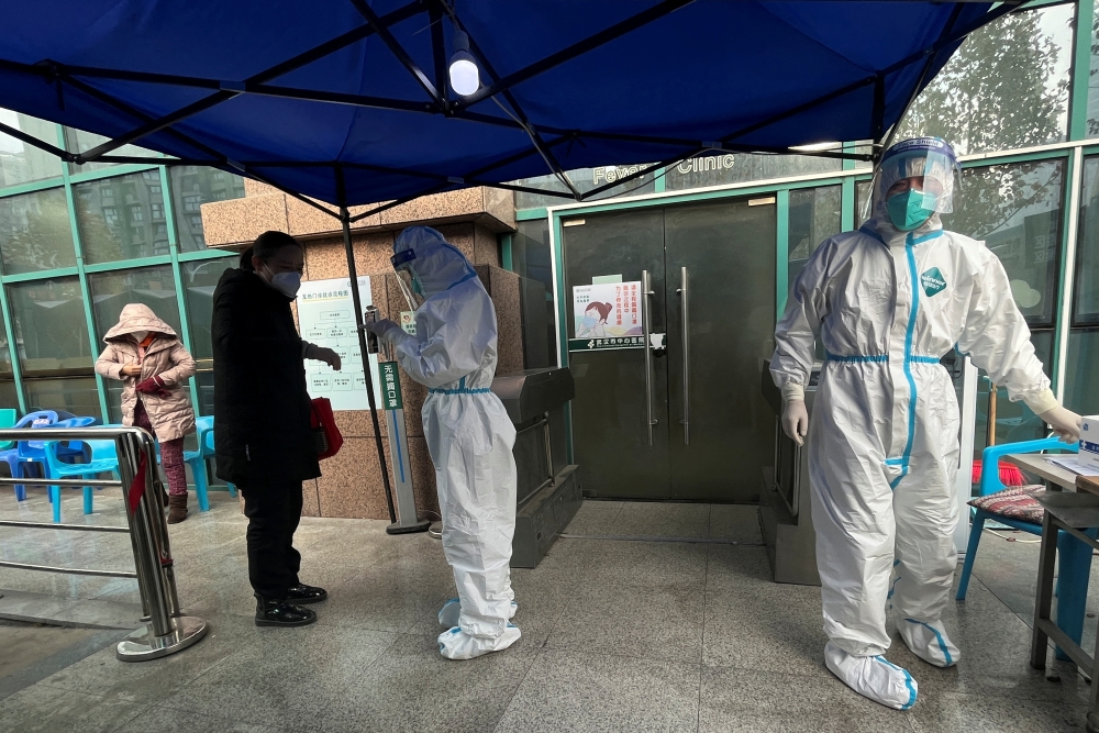 A medical worker in a protective suit checks a thermometer for a patient at the entrance to the fever clinic of the Central Hospital of Wuhan, amid of the coronavirus disease (COVID-19) outbreak, in Wuhan, Hubei province, China, on December 31, 2022. REUTERS/Tingshu Wang