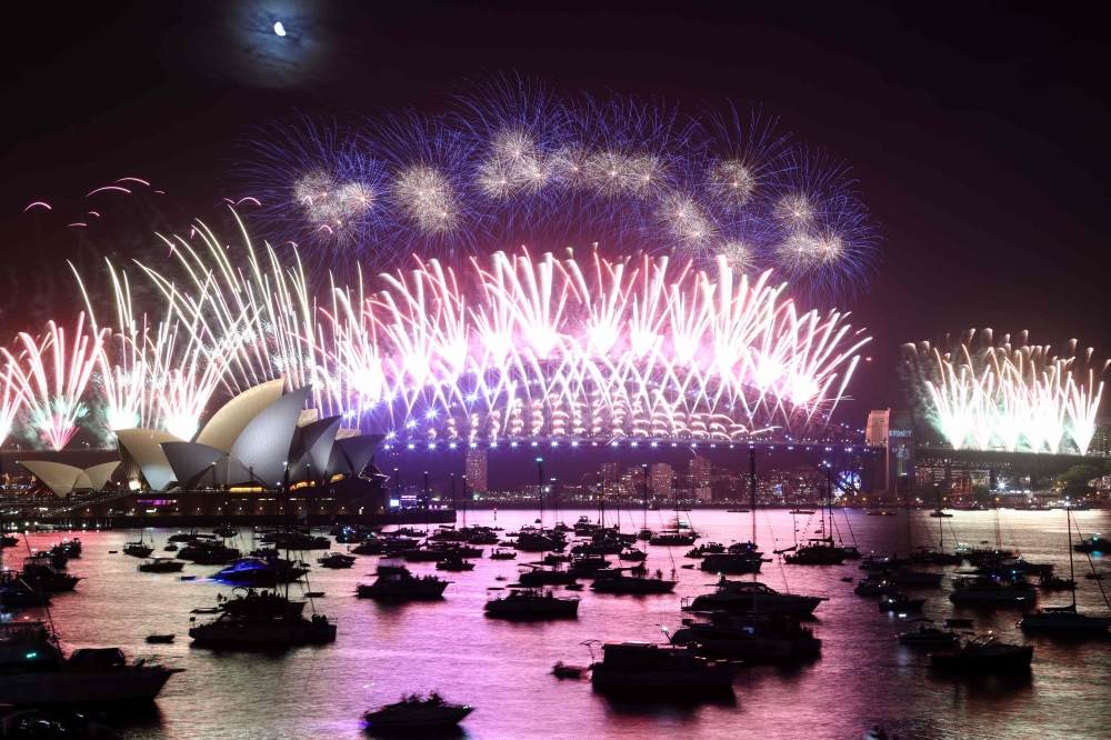 New Year's Eve fireworks light up the sky over the Sydney Opera House (L) and Harbour Bridge during the fireworks display in Sydney on January 1, 2023. (Photo by David Gray / AFP)