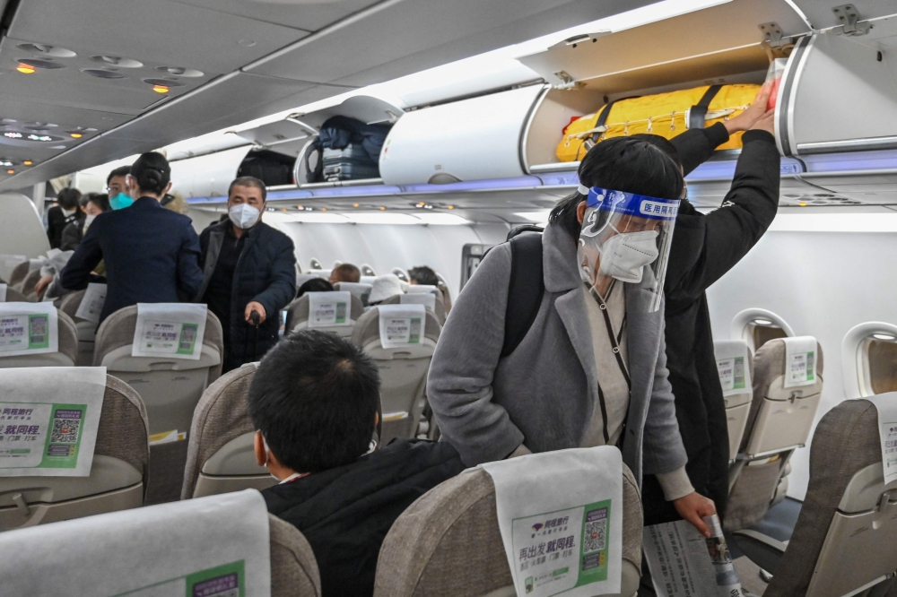 A passenger wearing a face shield and mask amid the Covid-19 pandemic boards a domestic flight at Shanghai Pudong International Airport in Shanghai on January 3, 2023. (Photo by HECTOR RETAMAL / AFP)