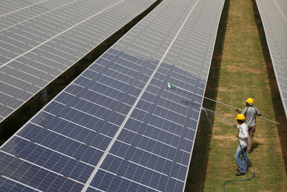 Workers clean photovoltaic panels inside a solar power plant in Gujarat, India, July 2, 2015. Reuters/Amit Dave/File Photo