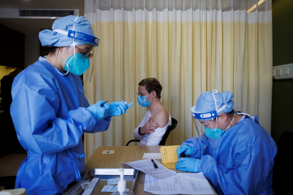 A nurse prepares a shot for Jonathan Halter as the German embassy begins its roll out of BioNTech COVID-19 vaccines for German expatriates at a Beijing United Family hospital in Beijing, China January 5, 2023. REUTERS/Thomas Peter