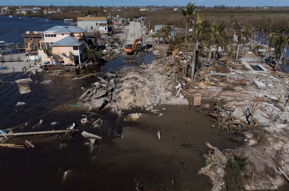 Onlookers stand at the edge of floodwaters on a residential street following heavy rains in the Windsor suburb of Sydney, Australia, July 5, 2022. (REUTERS/Loren Elliott)