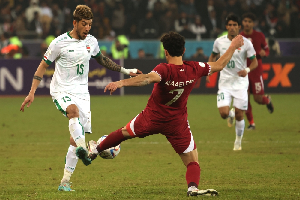 Iraq's defender Dhurgham Ismail (left) fights for the ball with Qatar's forward Ahmed Alaaeldin during the Arabian Gulf Cup semi-final football match between Iraq and Qatar at the Basra International Stadium in Iraq's southern city on January 16, 2023. (Photo by AHMAD AL-RUBAYE / AFP)