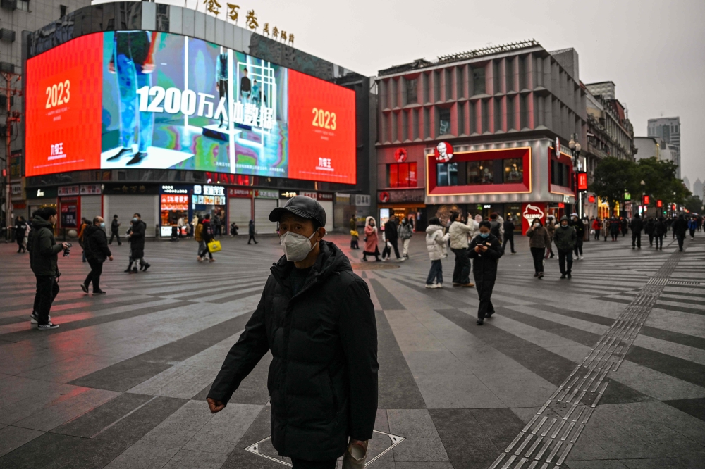 File photo: People walk on a street in Wuhan, in China's central Hubei province, on January 21, 2023. (Photo by Hector RETAMAL / AFP) 