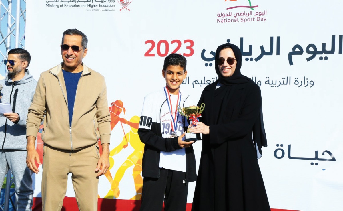 Minister of Education and Higher Education H E Buthaina bint Ali Al Jabr Al Nuaimi awards a student at a sport competition held as part of the ministry's National Sport Day activities. Undersecretary of the Ministry of Education and Higher Education Dr. Ibrahim bin Saleh Al Nuaimi is also seen.