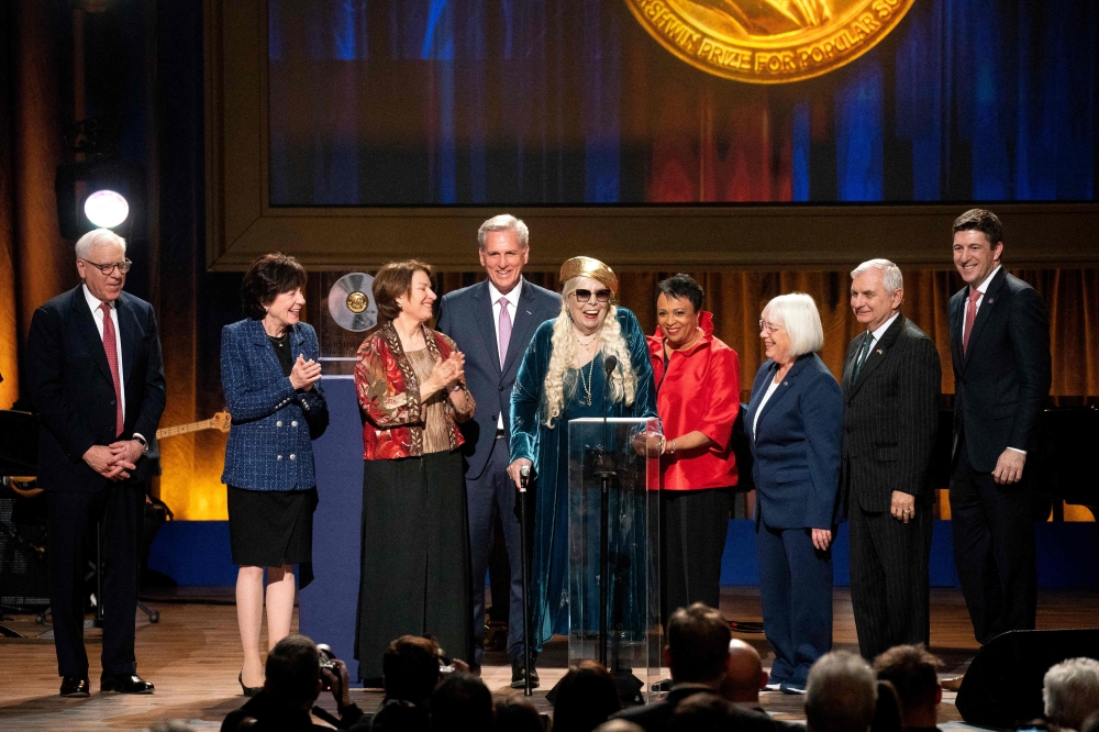 Honoree Canadian singer-songwriter Joni Mitchell speaks onstage during the Library of Congress Gershwin Prize for Popular Song ceremony in Washington, DC, March 1, 2023. - Also pictured are Senator Susan Collins, a Republican from Maine, Senator Amy Klobuchar, a Democrat from Minnesota, US House Speaker Kevin McCarthy, a Republican from California, Senator Patty Murray, a Democrat from Washington, and Senator Jack Reed, a Democrat from Rhode Island. (Photo by Stefani Reynolds / AFP)