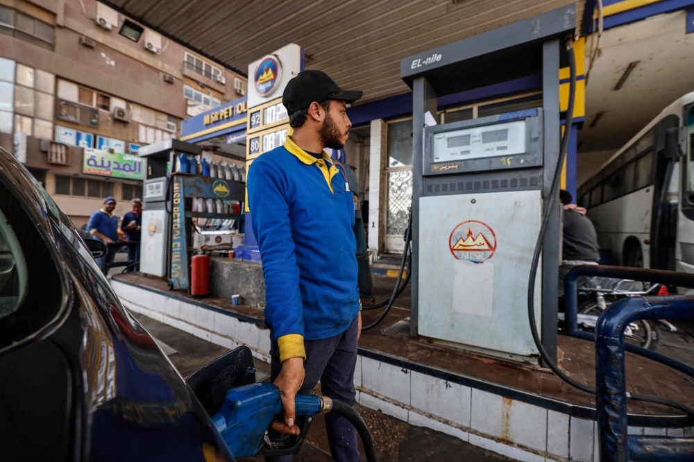 A worker fills the tank of a vehicle at a petrol station in Cairo on March 2, 2023 as Egypt's government announced a new increase in fuel prices. (Photo by Khaled Desouki / AFP)