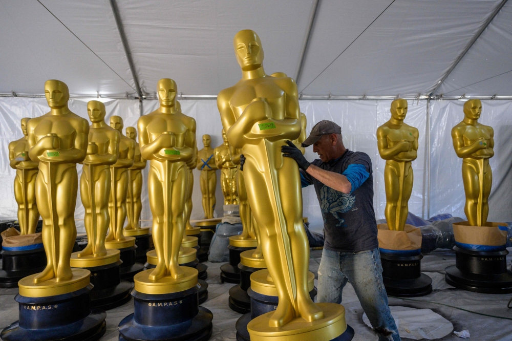 A worker lines up Oscar statues, as preparations are underway for the 95th Oscars Academy Awards, in Hollywood, California, on March 9, 2023. (Photo by ANGELA WEISS / AFP)