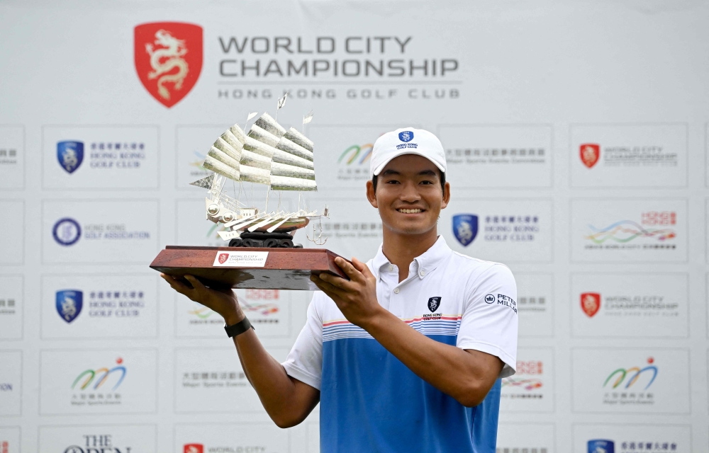 This handout photo taken and released by the Asian Tour on March 26, 2023 shows Hong Kong's Taichi Kho posing with the winner's trophy during round three of the World City Championship presented by the Hong Kong Golf Club. Photo by Paul LAKATOS / Asian Tour / AFP