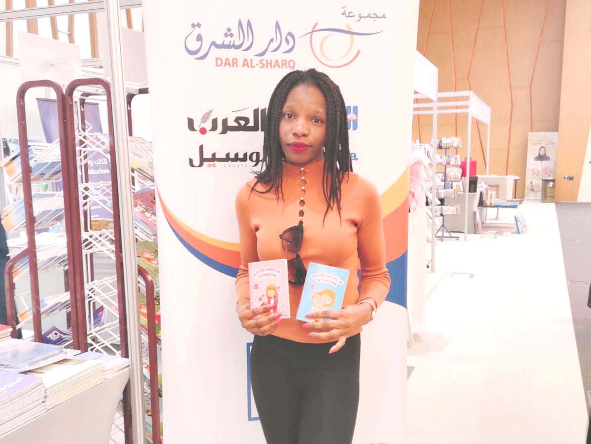 Helen Ogbelade stands with her books. 