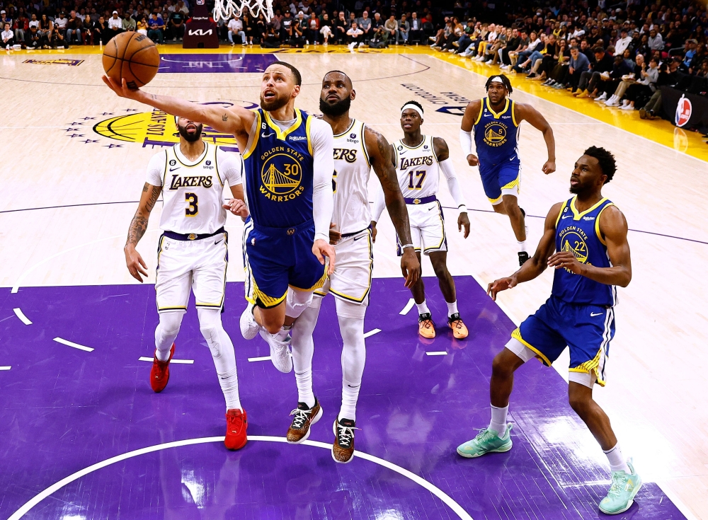 Stephen Curry #30 of the Golden State Warriors scores on a layup in front of LeBron James #6 of the Los Angeles Lakers. Ronald Martinez/Getty Images/AFP 
