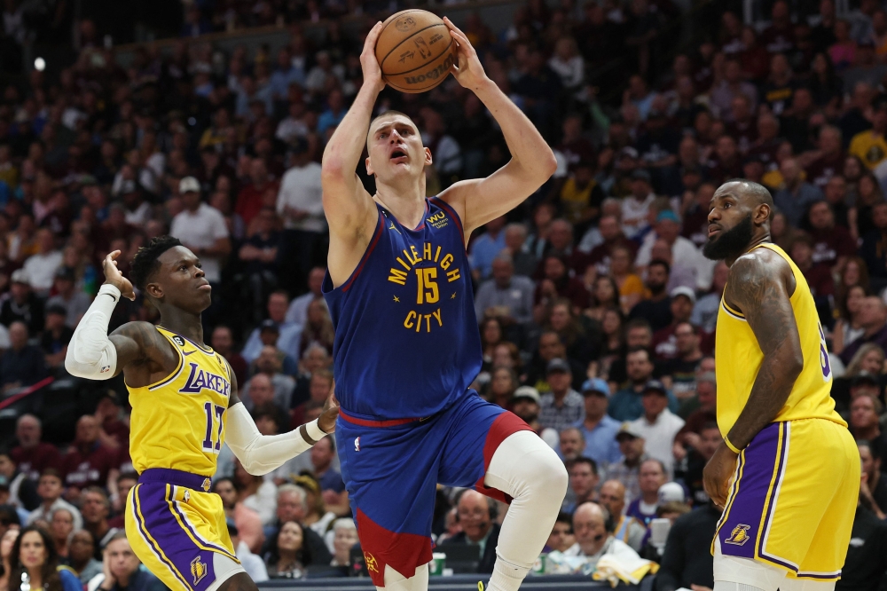 Nikola Jokic #15 of the Denver Nuggets shoots the ball between Dennis Schroder #17 and LeBron James #6 of the Los Angeles Lakers during the third quarter in game one of the Western Conference Finals at Ball Arena on May 16, 2023 in Denver, Colorado. Matthew Stockman/Getty Images/AFP 