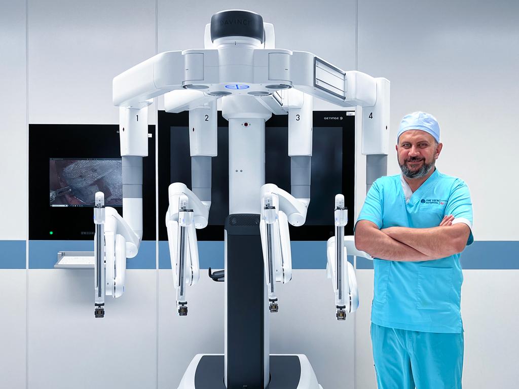 Surgeon Dr. Salaam Sadi standing next to the Da Vinci Xi® robotic surgery equipment