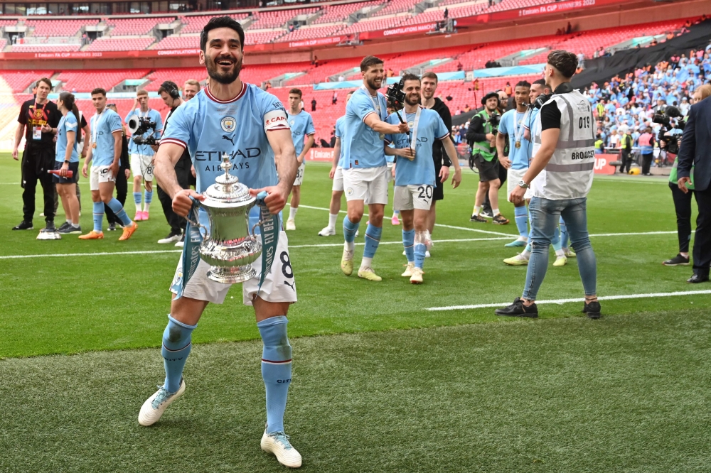 Manchester City's German midfielder Ilkay Gundogan celebrates with the trophy on the pitch after the English FA Cup final football match between Manchester City and Manchester United at Wembley stadium, in London, on June 3, 2023. Man City won the game 2-1. (Photo by Glyn KIRK / AFP) 