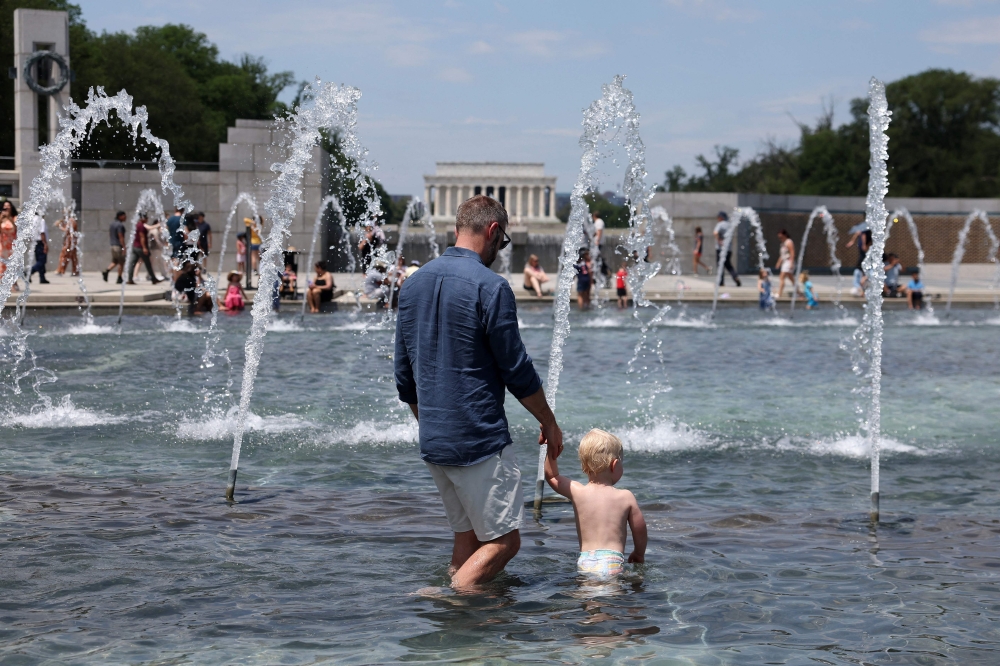 
Visitors and tourists to the World War II Memorial seek relief from the hot weather in the memorial's fountain on July 3, 2023 in Washington, DC. (Photo by Kevin Dietsch/Getty Images via AFP)