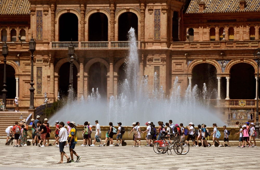 A group of schoolchildren on a excursion cool off walking along a fountain at the Plaza Espana square in Seville on April 26, 2023 as Spain is bracing for an early heat wave. (Photo by CRISTINA QUICLER / AFP)