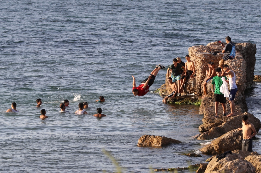 A Libyan dives into the water in Tripoli on July 6, 2023, during a heatwave. (Photo by Mahmud Turkia / AFP)