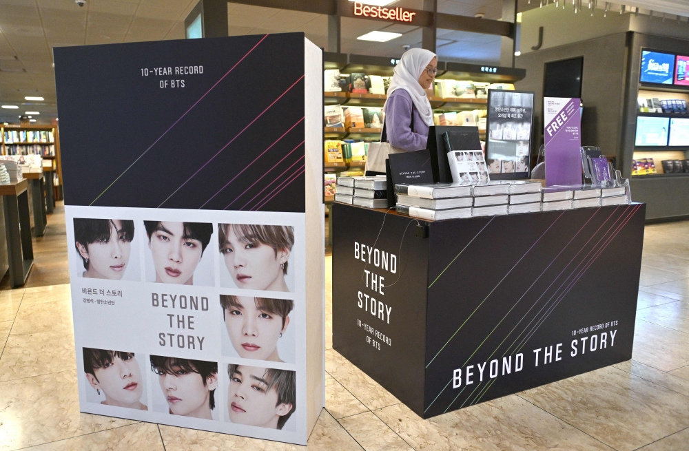 A woman looks at copies of the BTS memoir titled 