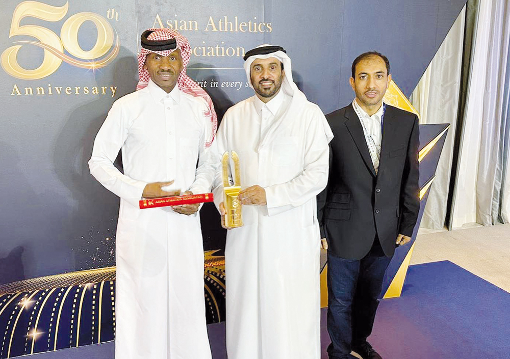 QAF President Mohammed Issa Al Fadala, holding Mutaz Barshim's award, poses for a picture with Essa Barshim yesterday.   