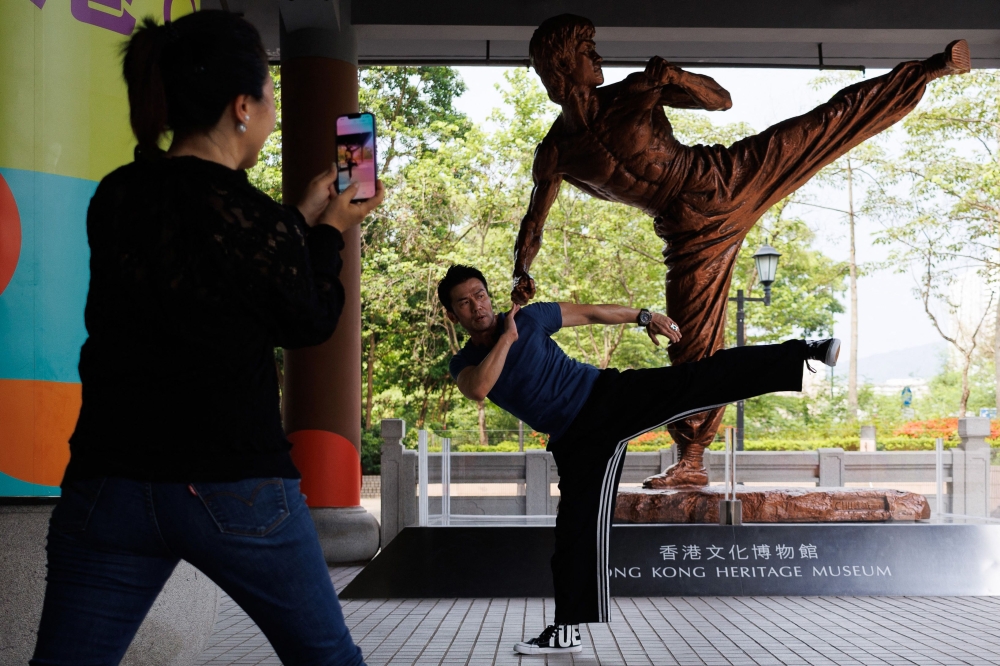 In this photo taken on July 15, 2023 visitors take pictures with a statue of Bruce Lee outside the Hong Kong Heritage Museum in Hong Kong, ahead of the 50th anniversary of the martial arts star's death on July 20. Photo by May JAMES / AFP