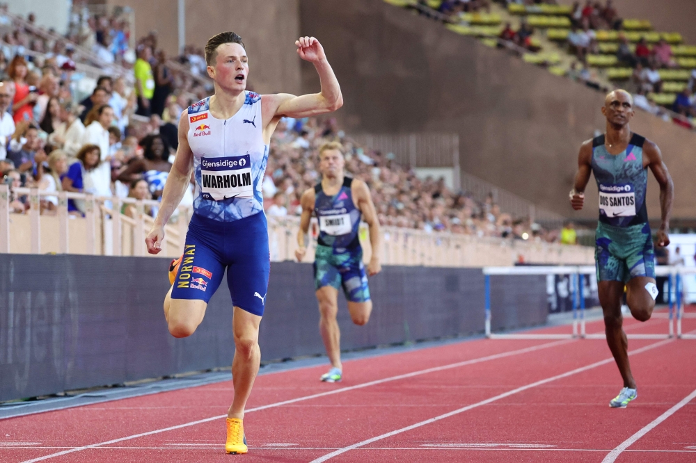 Karsten Warholm of Norway (L) crosses the finish line ahead of Alison Dos Santos of Brazil (R) in the Men's 400m Hurdles event in Monaco, on July 21, 2023. (Photo by Clement Mahoudeau / AFP)