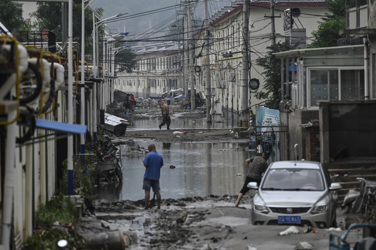 A local resident cleans up the street in the aftermath of the flooding at a village following heavy rains in Beijing on August 3, 2023. Photo by Jade Gao / AFP