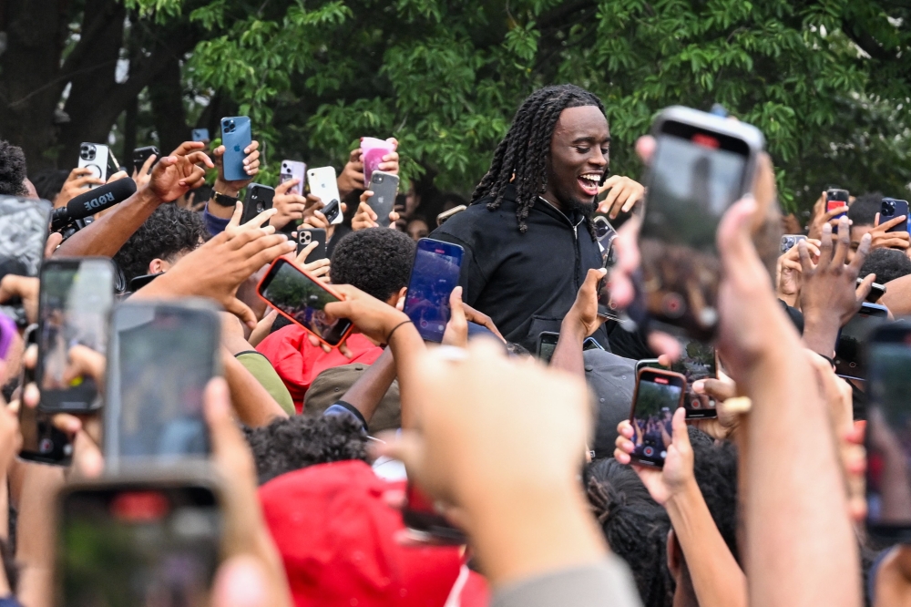 People gather around and cheer for Kai Cenat (C) as members of the NYPD respond to thousands of people gathered for a 