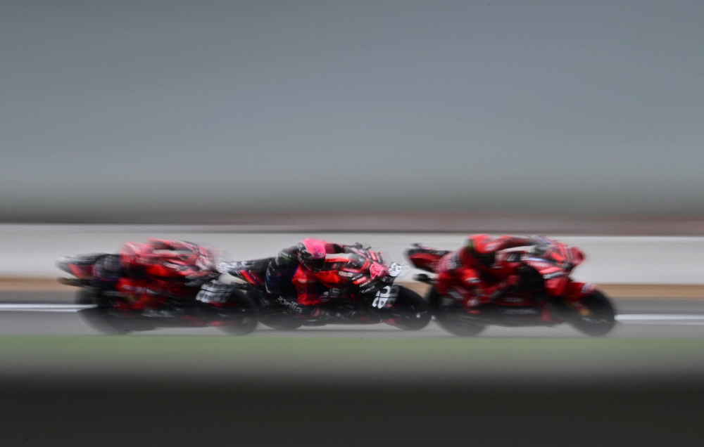 Eventual race winner, Aprilia Racing Spanish rider Aleix Espargaro (C) is sandwiched between Aprilia Racing Spanish rider Maverick Vinales (L) and Ducati Lenovo Team Italian rider Francesco Bagnaia (R) during the Moto GP race of the motorcycling British Grand Prix at Silverstone circuit in Northamptonshire, central England, on August 6, 2023. (Photo by Ben Stansall / AFP)
