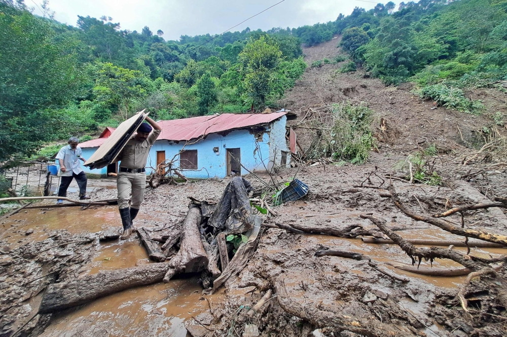 A security personnel carries the belongings of a villager from the site of a landslide after heavy rains at Jadon village in Solan district of India's Himachal Pradesh state on August 14, 2023. Photo by AFP