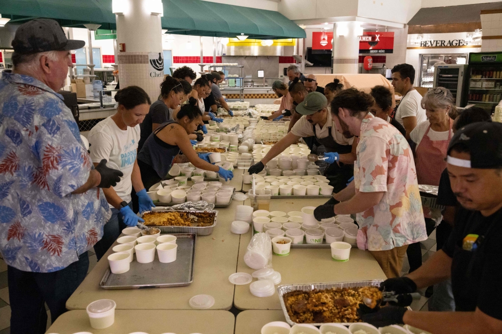 Volunteers prepare free meals to donate to West Maui families affected by wildfires, at the University of Hawaii Maui College in Kahului, central Maui, Hawaii on August 13, 2023. (Photo by Yuki Iwamura / AFP)